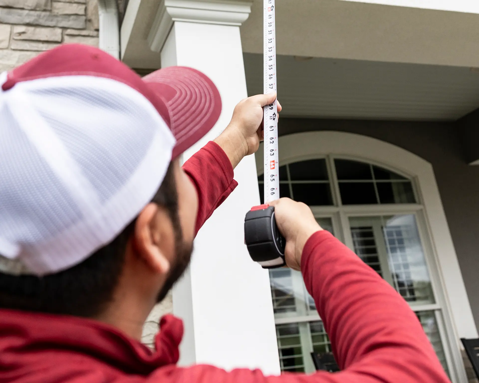 man measuring the front of a house